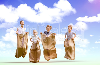 Composite image of friends playing sack race