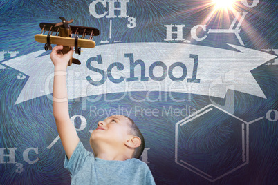 Composite image of boy holding wooden toy airplane