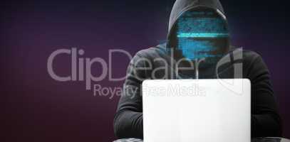 Composite image of hacker wearing black hood while using laptop on table