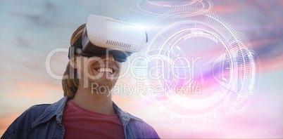 Composite image of smiling young man wearing virtual reality simulator