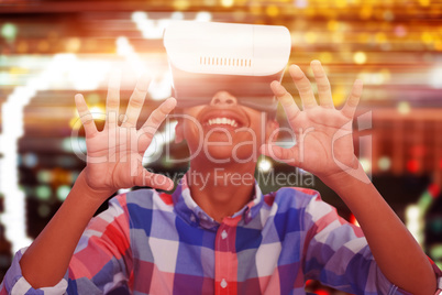 Composite image of happy boy looking through virtual reality simulator while sitting on chair