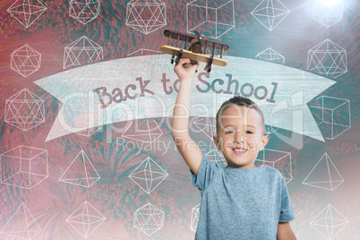 Composite image of portrait of boy holding toy airplane