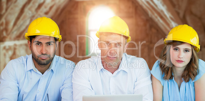 Composite image of portrait of architects wearing hardhats while sitting at table