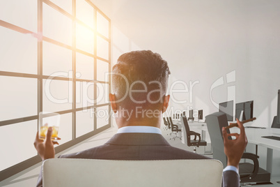 Composite image of rear view of businessman holding whisky glass and cigar