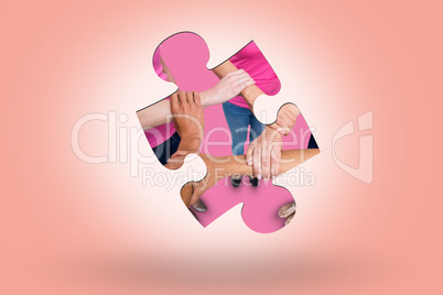 Composite image of women in pink outfits joining in a circle for breast cancer awareness