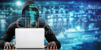 Composite image of male hacker using laptop on table