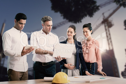 Composite image of male architect showing laptop to coworkers