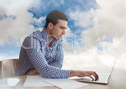 Man on laptop in cloudy sky