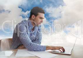 Man on laptop in cloudy sky