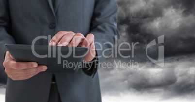 Businessman using tablet under sky clouds