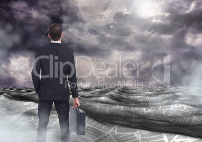 Businessman holding briefcase in sea of documents under dark sky clouds