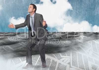 Businessman opening arms in sea of documents under sky clouds