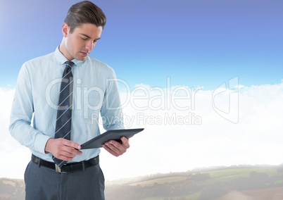 Businessman using tablet under sky clouds