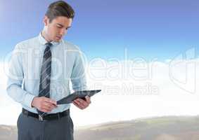 Businessman using tablet under sky clouds
