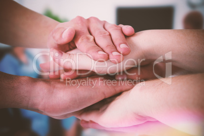 Composite image of cropped image of people forming hands stack