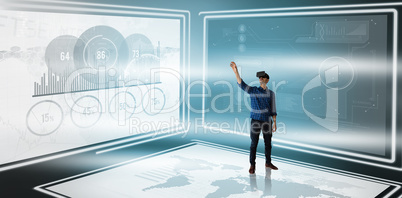 Composite image of businessman gesturing while looking though virtual reality simulator