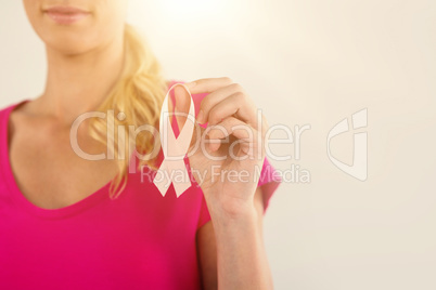 Mid section of woman holding pink breast cancer awareness ribbon