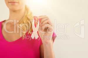 Mid section of woman holding pink breast cancer awareness ribbon