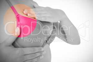 Mid section of woman in pink bra examining breast for cancer awareness