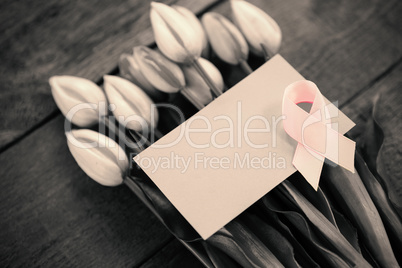 High angle view of pink Breast Cancer Awareness ribbon with blank card on tulips