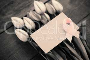 High angle view of pink Breast Cancer Awareness ribbon with blank card on tulips