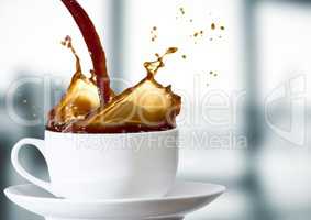 Coffee being poured into white cup against blurry grey office