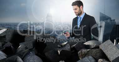 Dark bricks in pile with businessman holding phone over city