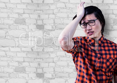 Frustrated millennial man against white brick wall
