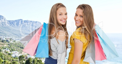 Women with shopping bags against blurry coastline