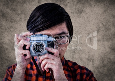 Close up of millennial man with camera against brown background with grunge overlay