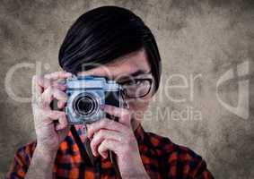 Close up of millennial man with camera against brown background with grunge overlay