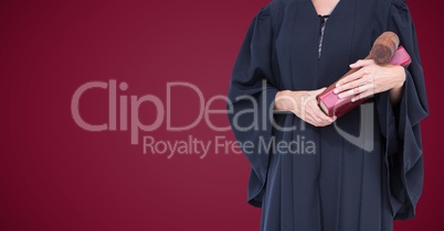 Female judge mid section with book and gavel against maroon background