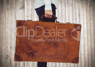 Millennial woman lower body with suitcase against blurry wood panel