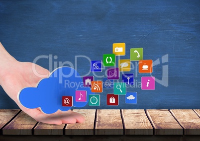 hand rest on a table with cloud over and application icons coming up form it. Blue wall behind