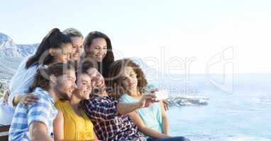 Friends taking group photo against blurry coastline