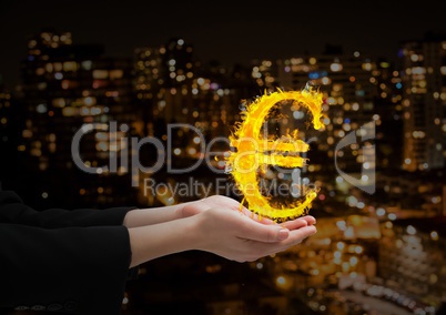 hand with euro fire icon over in front of the blurred city at night