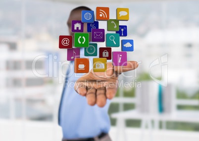 businessman (blurred) with hand spread of with application icons over. Blurred office background