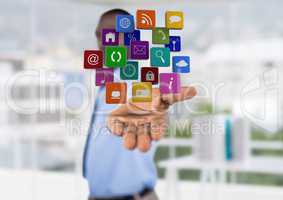 businessman (blurred) with hand spread of with application icons over. Blurred office background