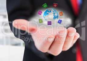 Businessman hand with application icons around earth with cloud behind.