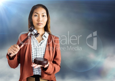 Female judge with gavel against blue cloudy sky with flares