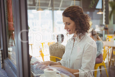 Woman using laptop seen through glass window