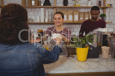 Female owner serving coffee and muffin to customer