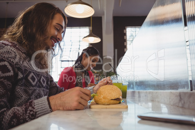 Man with friend having burger in cafe