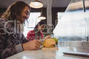 Man with friend having burger in cafe