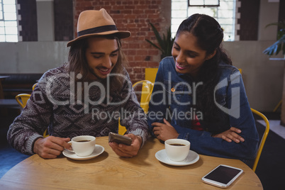 Man with friend using phone in cafe