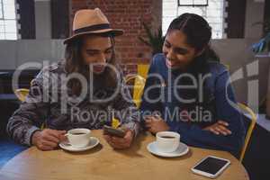 Man with friend using phone in cafe