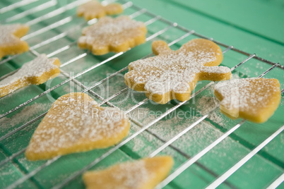 High angle view of powdered sugar on cookies over cooling rack