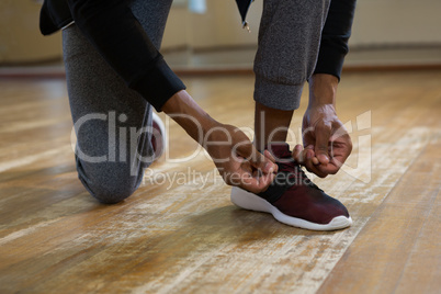 Low section of dancer tying shoelace on floor