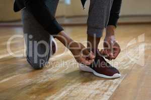 Low section of dancer tying shoelace on floor