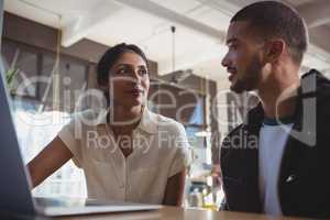 Couple with laptop looking each other in cafe